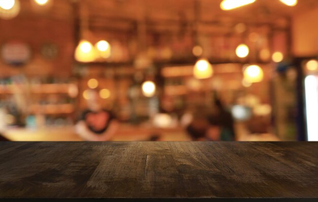 La table en bois vide devant l'arrière-plan flou abstrait du café peut être utilisée pour l'affichage ou le montage de vos produits Maquette pour l'affichage du produit