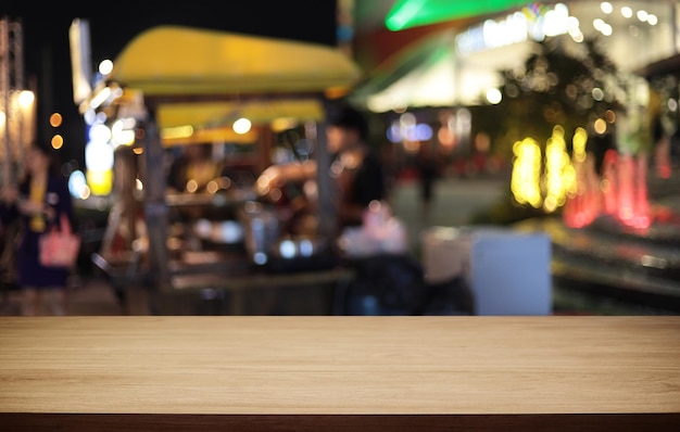 La table en bois vide devant l'arrière-plan flou abstrait du café peut être utilisée pour l'affichage ou le montage de vos produits Maquette pour l'affichage du produit