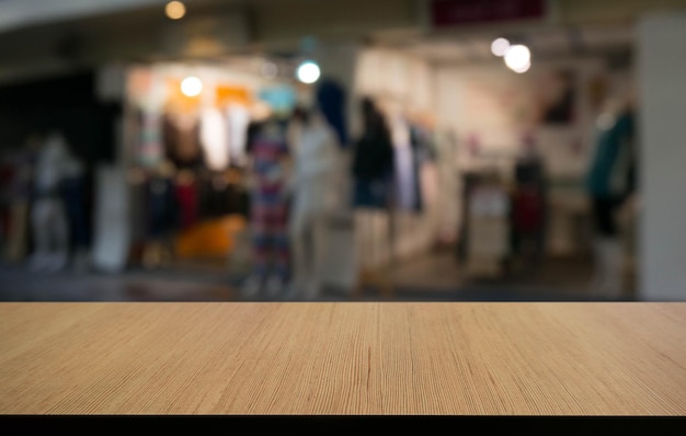 Une table en bois vide devant l'arrière-plan flou abstrait du café peut être utilisée pour l'affichage ou le montage de vos produits.