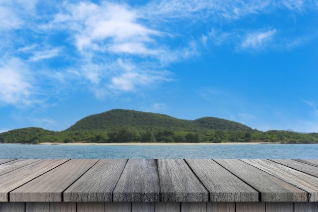 Table en bois vide sur fond de ciel de mer et de montagne pour la conception dans votre concept d'été de travail.