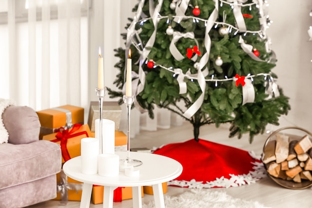 Table avec bougies et arbre de Noël à la maison. Intérieur de la salle de fête