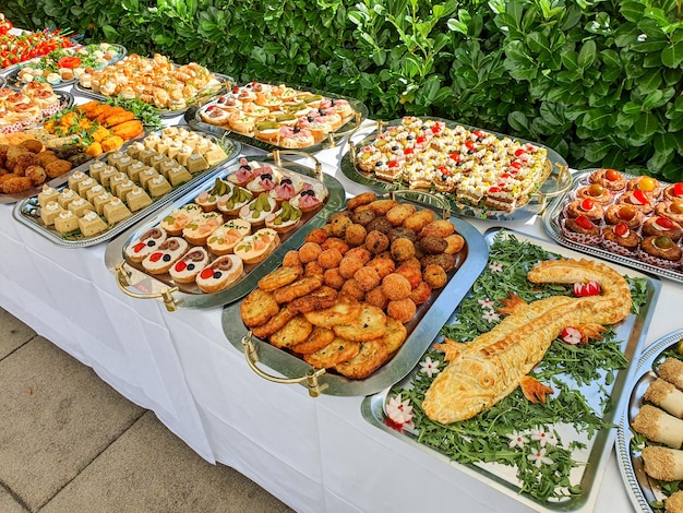 Une table de buffet avec une variété de plats, y compris des sandwichs et des salades.