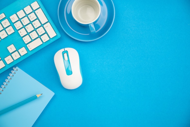 Table de bureau d'affaires avec des objets métier de clavier, souris, crayon, note de papier et tasse à café sur fond bleu