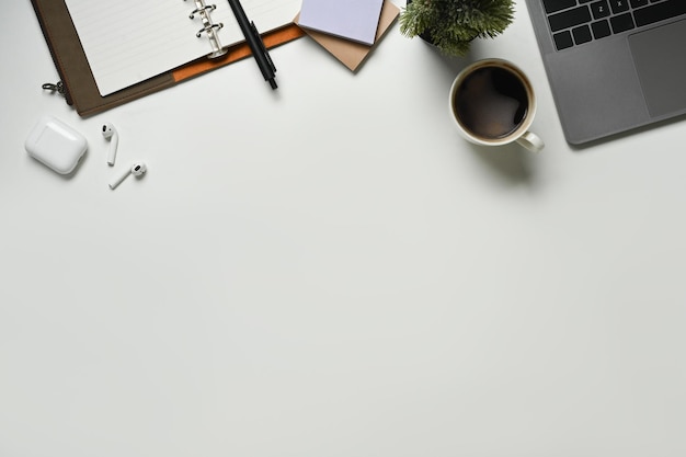 Table de bureau blanche moderne avec ordinateur portable tasse de café et bloc-notes Vue de dessus avec espace de copie mise à plat