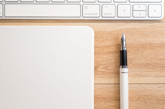 Table de bureau avec bloc-notes, clavier et stylo plume. Vue d'en-haut