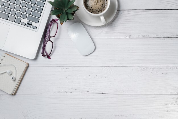 Table de bureau en bois blanc avec ordinateur portable et café sur bois blanc