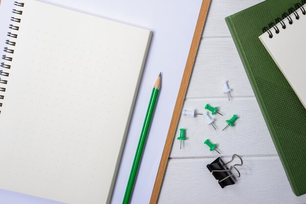 Table de bureau en bois blanche avec une tasse de café, un cahier, un stylo dessus.