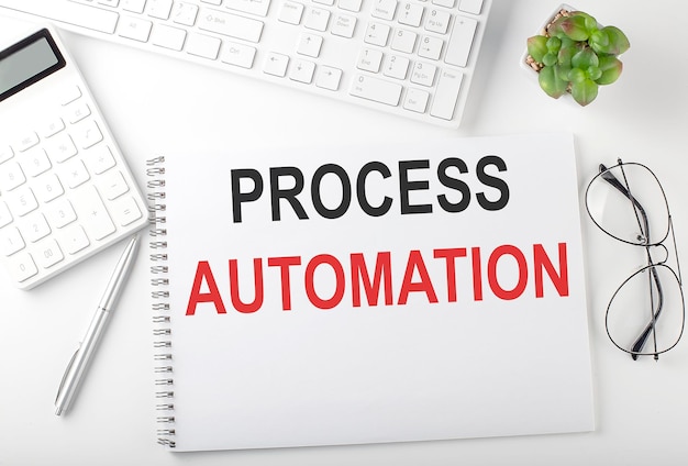 Table de bureau avec clavier, bloc-notes et calculatrice. Vue de dessus avec texte PROCESS AUTOMATION