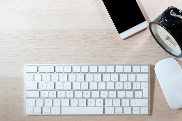 Table de bureau avec clavier, souris, smartphone et réveil