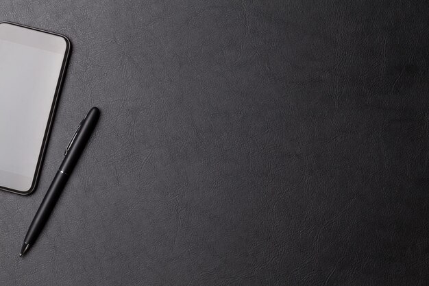 Table de bureau en cuir avec smartphone et stylo