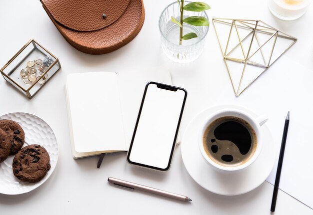 Table de bureau à domicile blanche avec tasse à café et bloc-notes de maquette de smartphone