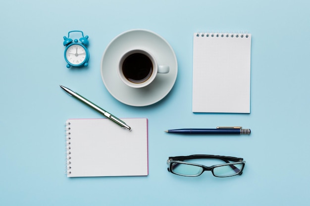 Table de bureau moderne avec bloc-notes et autres fournitures avec une tasse de café Page de bloc-notes vierge pour votre conception Vue de dessus mise à plat