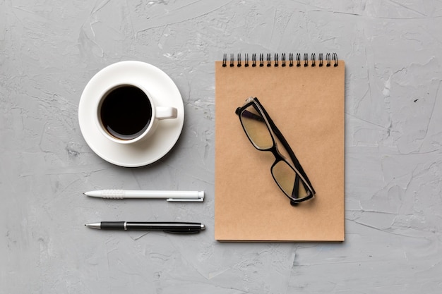 Table de bureau moderne avec bloc-notes et autres fournitures avec une tasse de café Page de bloc-notes vierge pour votre conception Vue de dessus mise à plat