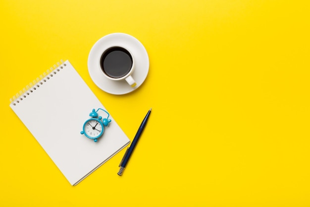 Table de bureau moderne avec bloc-notes et autres fournitures avec une tasse de café Page de bloc-notes vierge pour votre conception Vue de dessus mise à plat