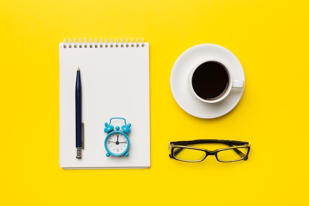 Table de bureau moderne avec bloc-notes et autres fournitures avec une tasse de café Page de bloc-notes vierge pour votre conception Vue de dessus mise à plat