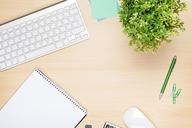 Table de bureau avec ordinateur bloc-notes et fleur