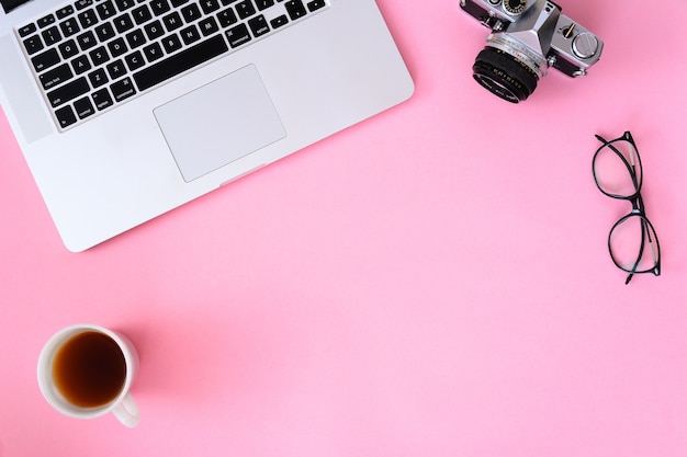 Table de bureau avec ordinateur portable, appareil photo et lentilles café.