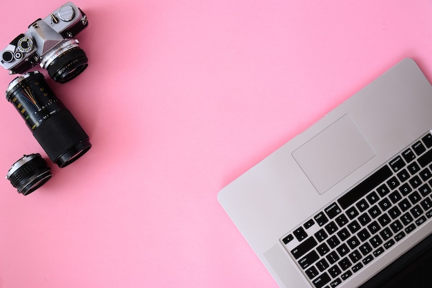 Table de bureau avec ordinateur portable, appareil photo et lentilles café.