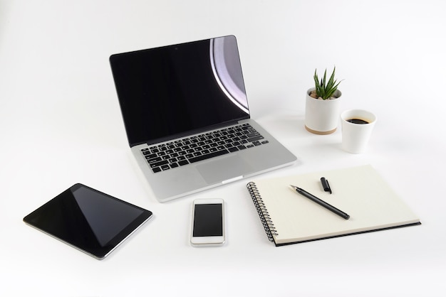 Table de bureau avec ordinateur portable, ordinateur portable, tablette numérique et smartphone sur fond blanc.