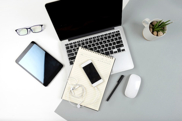 Table de bureau avec ordinateur portable, ordinateur portable, tablette numérique et téléphone portable sur deux tons b