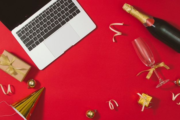 Table de bureau à plat, vue de dessus. Espace de travail avec ordinateur portable et décorations de noël sur surface rouge