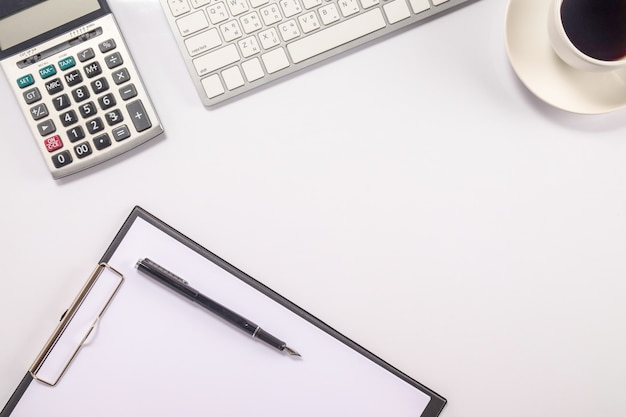 Table de bureau avec stylo, clavier sur ordinateur portable, tasse de café et fleur. Vue de dessus avec copie (focus sélectif).