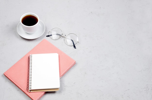 Table de bureau de travail gris avec cahiers, vide vide, fournitures, verres et tasse de café