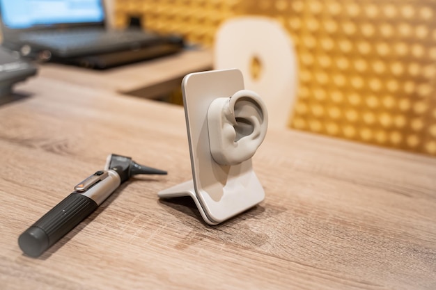 Table d'un cabinet médical avec un otoscope et un modèle d'oreille avec une prothèse auditive