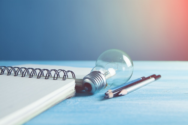 Sur la table un cahier, des stylos et une ampoule