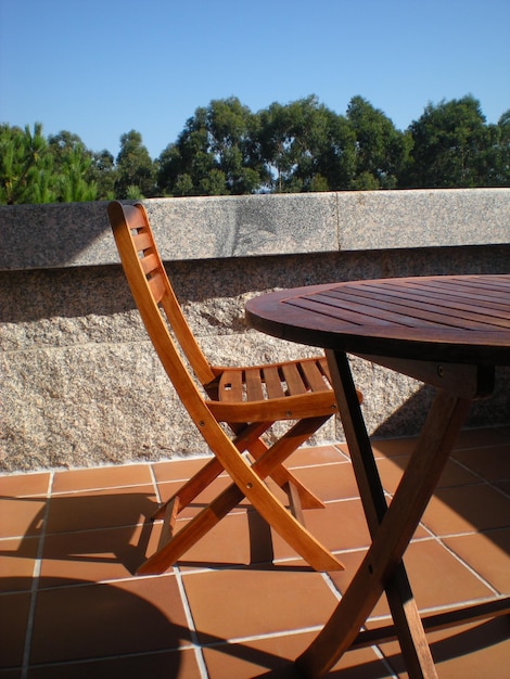 Photo une table et une chaise en bois sur un balcon avec un ciel bleu en arrière-plan.