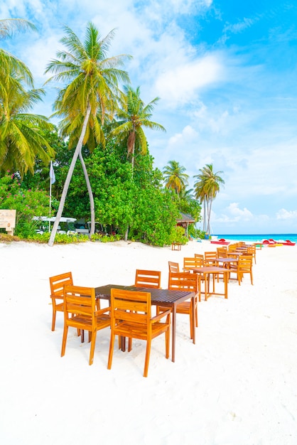 table et chaise en bois sur la plage avec vue sur la mer aux Maldives