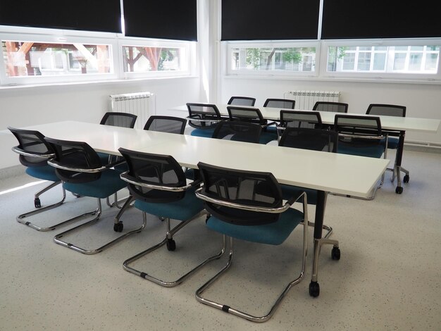 Table et chaises dans la salle de réunion au bureau Stores noirs pour assombrir la pièce Intérieur moderne