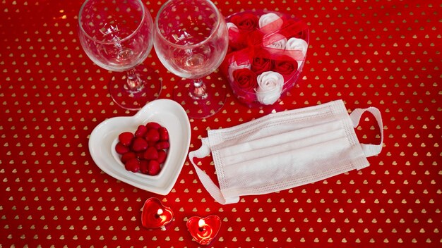 Table conceptuelle de la Saint-Valentin. dîner romantique avec masque médical. Coronavirus 2021. Masque de protection faciale et décor de table rouge