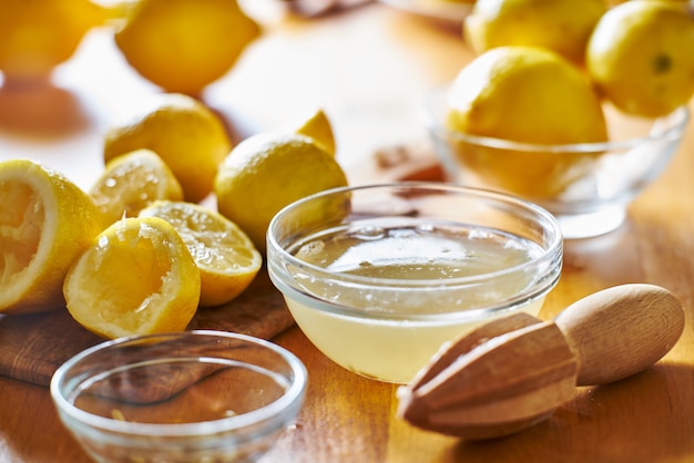 Table de cuisine avec bol plein de jus de citron fraîchement pressé avec alésoir en bois