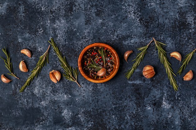 Table de cuisine sombre avec romarin, ail et poivre.