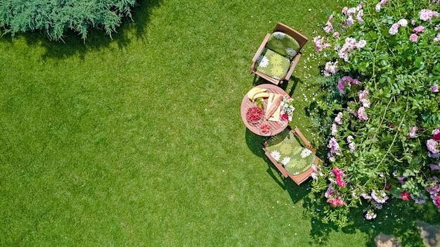 Table décorée avec du pain aux fraises et des fruits dans la belle vue aérienne de la roseraie d'été