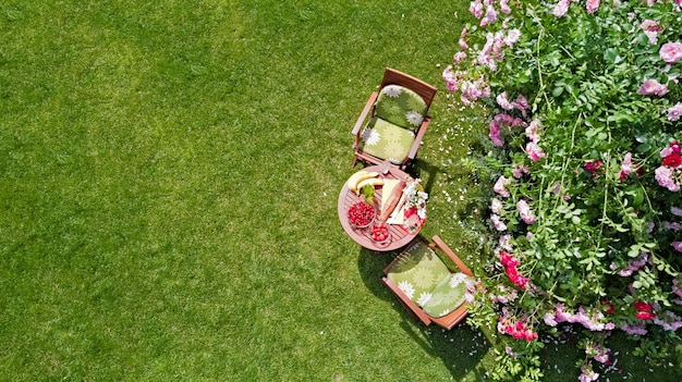 Table décorée avec du pain fraise et fruits dans la belle vue aérienne de drone de roseraie d'été