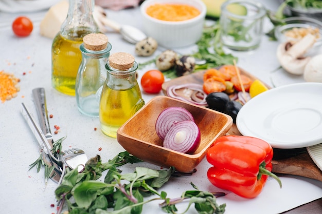 Table désordonnée pleine d'ingrédients pour la salade Olives oignons huile et verts