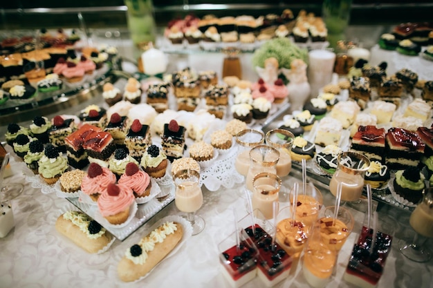 Table de desserts de bar à bonbons de réception de mariage avec de délicieux gâteaux et biscuitsx9