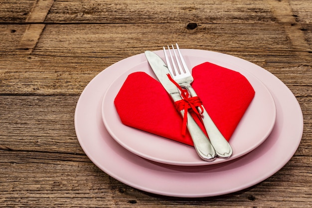 Table de dîner romantique avec assiettes et serviette en forme de coeur