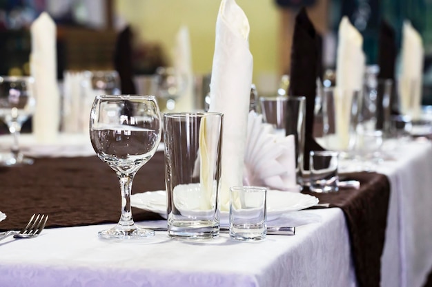 Table dressée dans le restaurant nappes blanches verres et verres à liqueur libre mise au point sélective