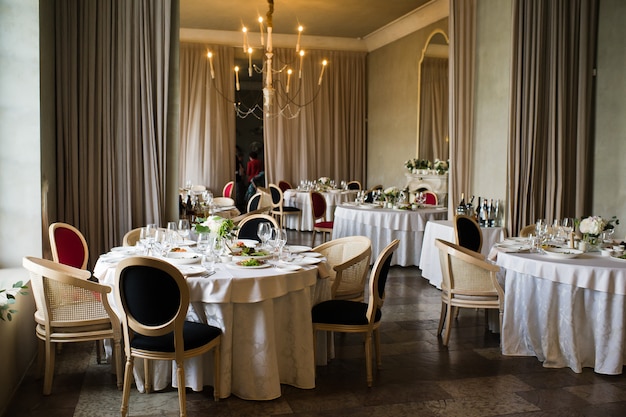 Table dressée lors du banquet de mariage au restaurant, style classique avec nappes et serviettes blanches, vases à fleurs.