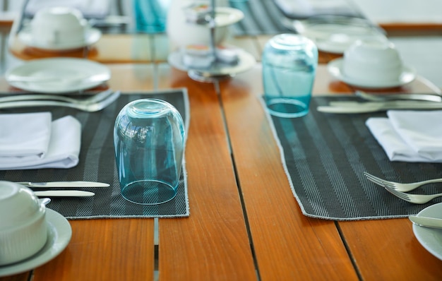 Une table dressée pour un repas avec des nappes à rayures bleues et grises et de l'argenterie.