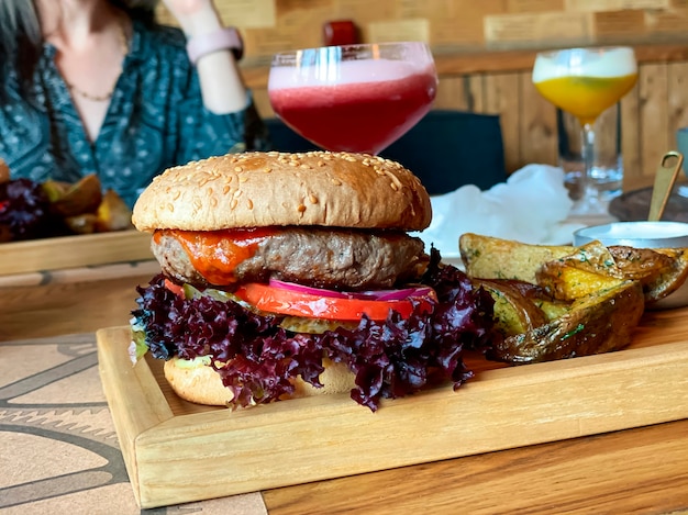 Sur la table du restaurant un burger avec une escalope de veau une rondelle d'oignon rouge basilic une tomate une