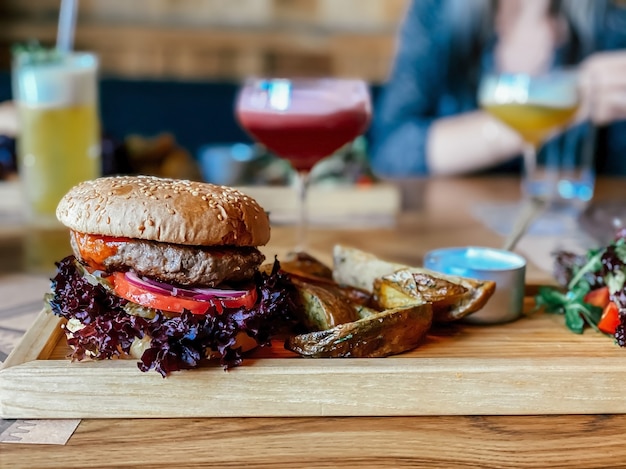 Sur la table du restaurant un burger avec une escalope de veau une rondelle d'oignon rouge basilic une tomate une