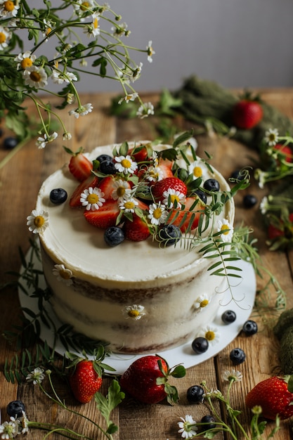 Sur la table est un gâteau décoré de baies et de fleurs