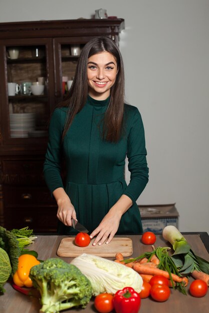 À la table, la femme coupe une tomate