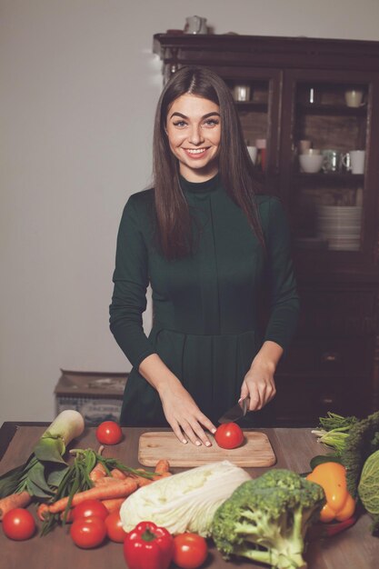 À la table, la femme coupe une tomate