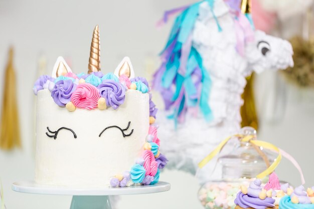 Table de fête d'anniversaire de petite fille avec gâteau de licorne, cupcakes et biscuits au sucre.