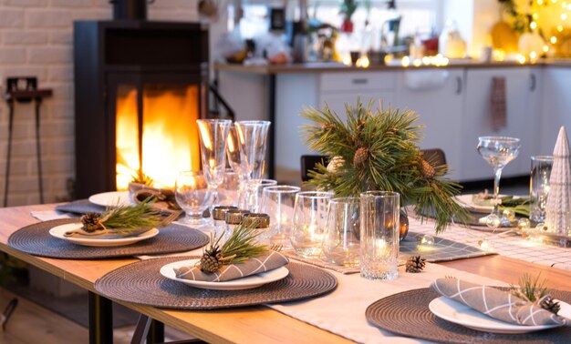 Table de fête avec assiettes fourchettes couteaux serviettes verres gros plan près du poêle cheminée